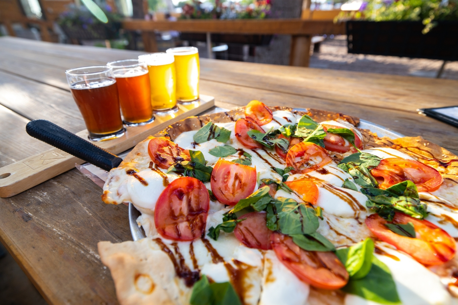 A flight of beers with a gooey pizza