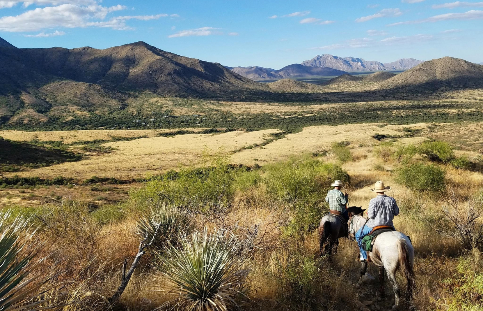 Two horseback riders in the desert on a dude ranch vacation.