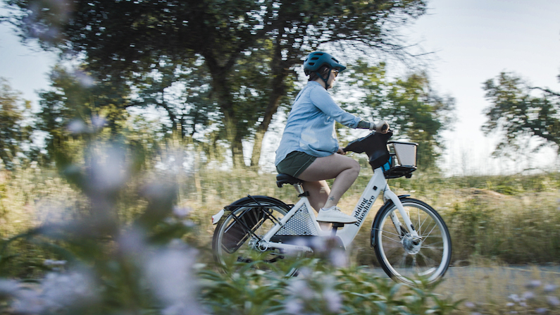 Biker riding past flowers and trees on Sacramento River Trail in Redding, California