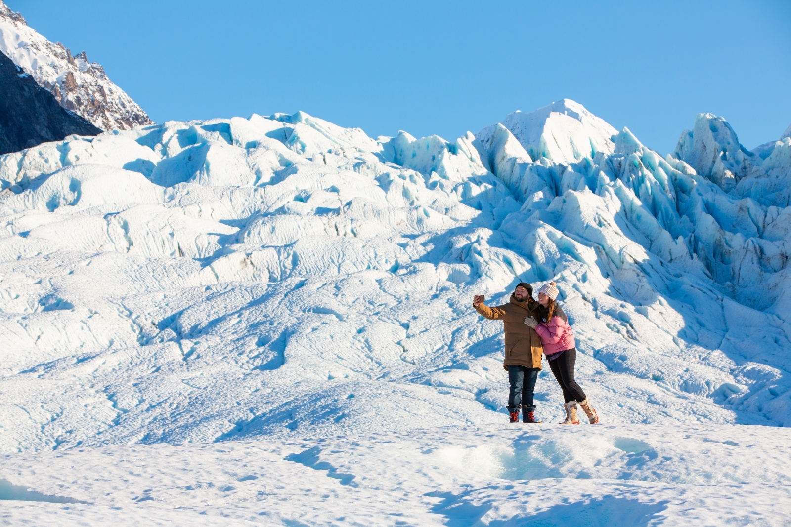 Two people posing for a photo on a glacier