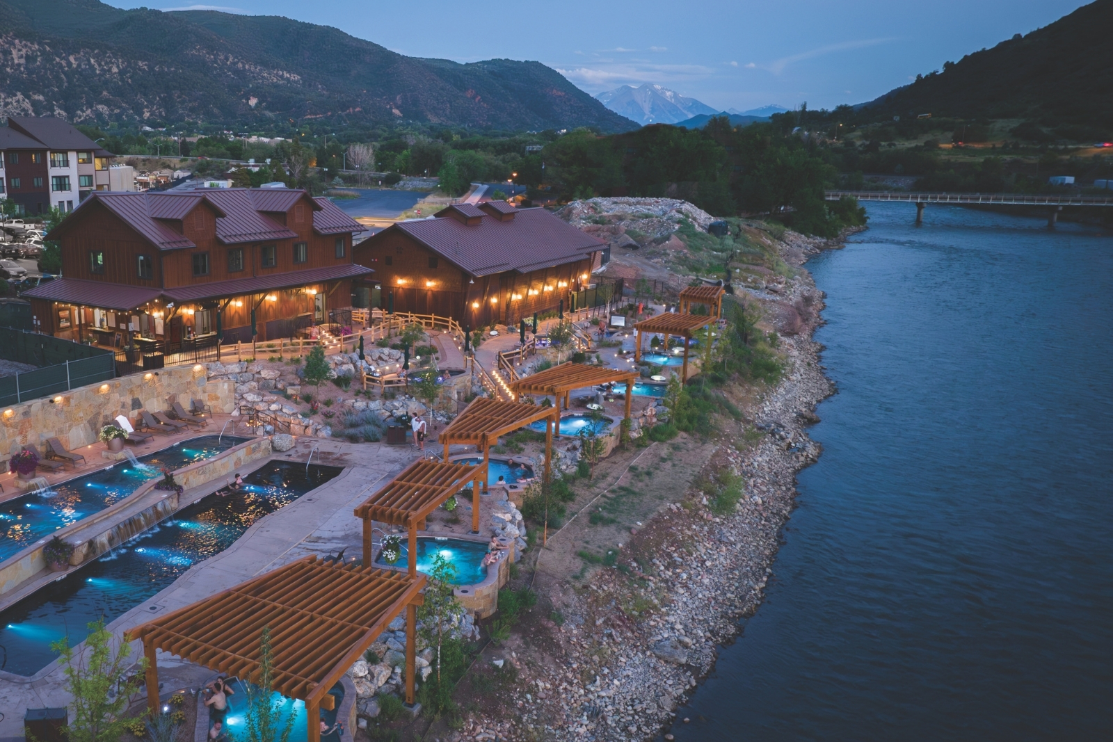 Aerial view of hot springs next to a river at dusk.